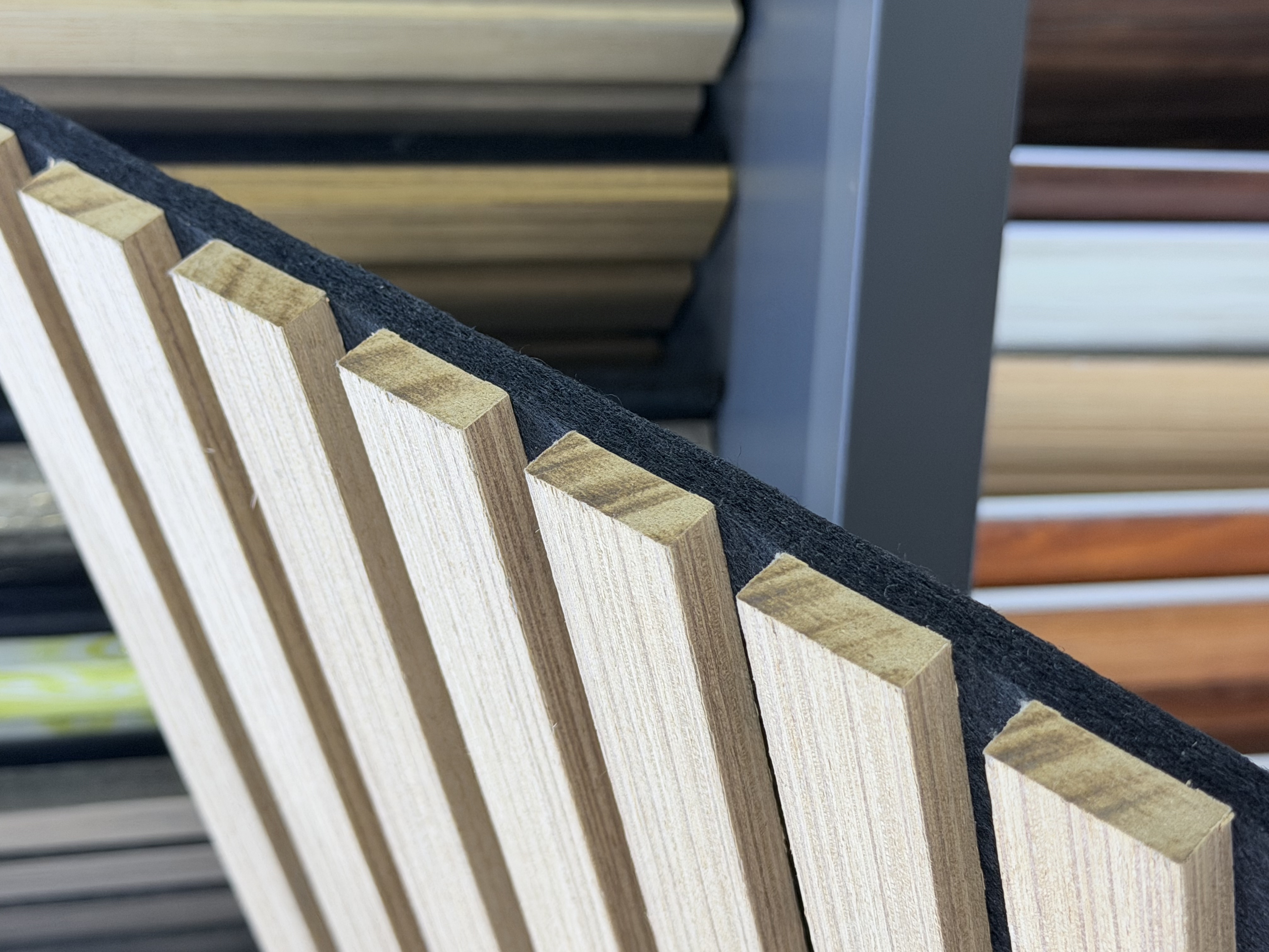 Close-up of slat panel edge showing wood slat thickness and black PET backing